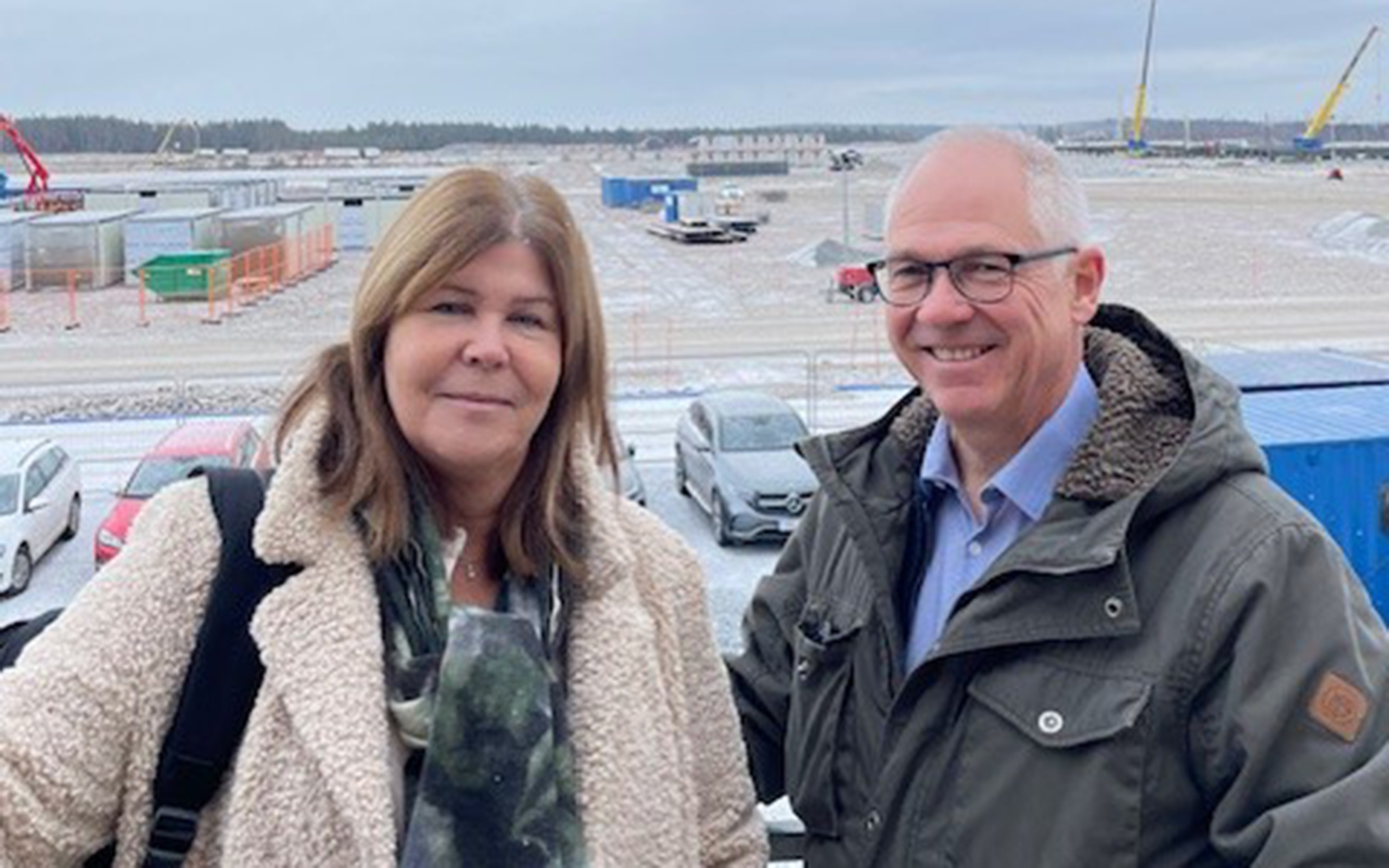 En kvinna och en man står utomhus på en parkering.